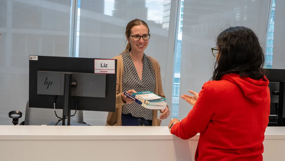 A librarian checking out a book to a patron